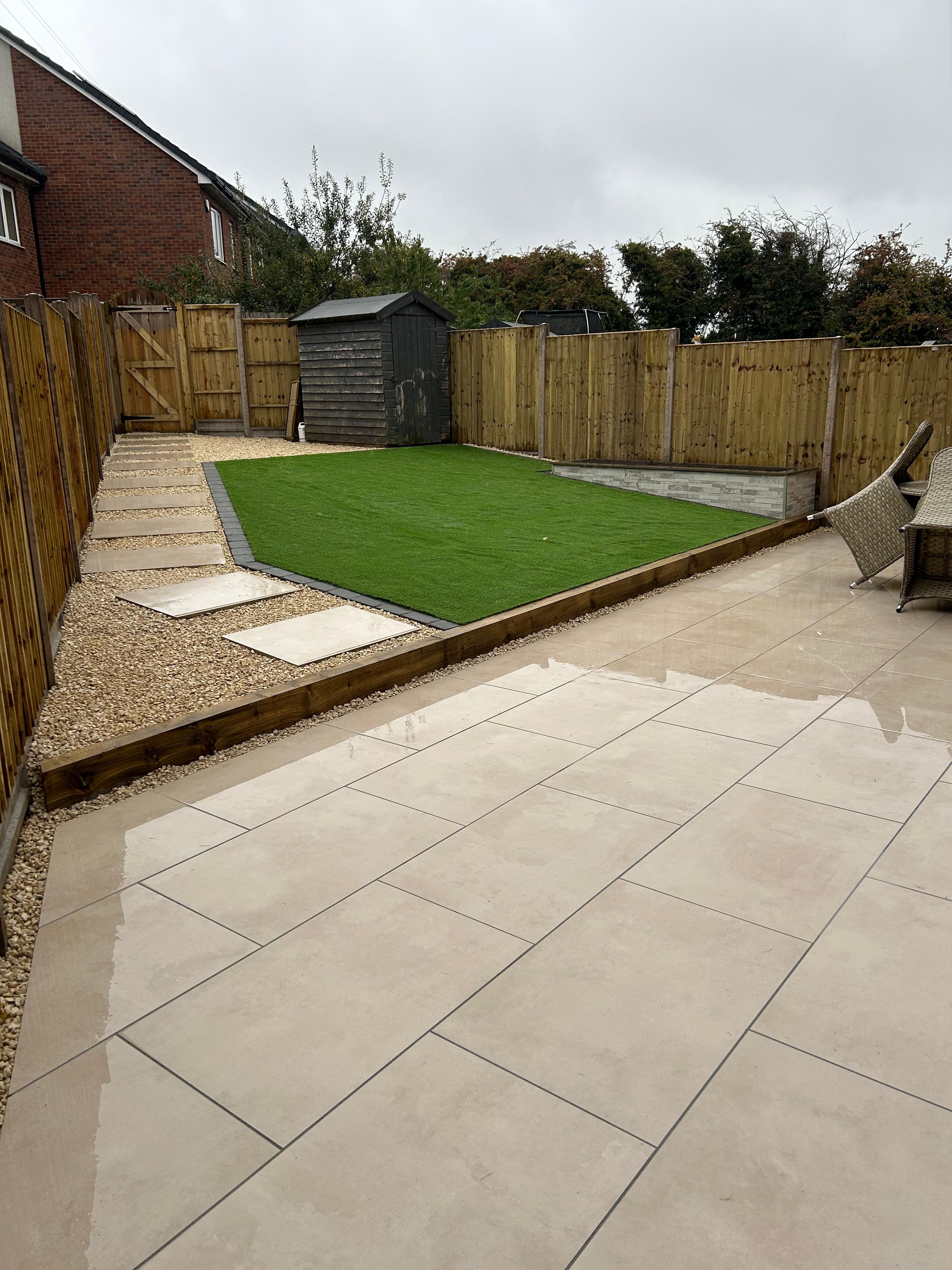Paved seating area, neat green lawn, stepping-stone path and new timber fencing in a Progreen garden photograph
